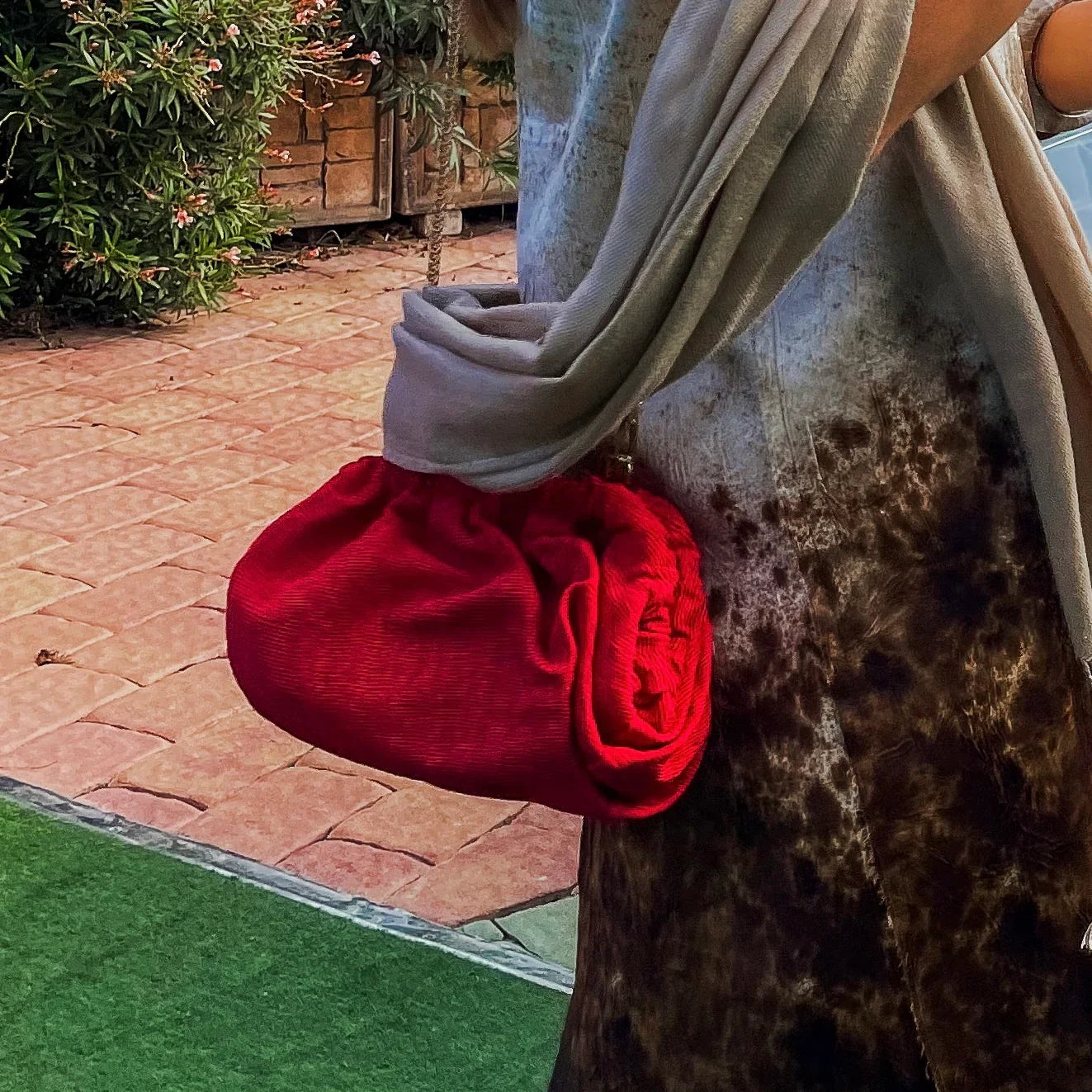 Red fabric clutch held by a woman at a wedding venue
