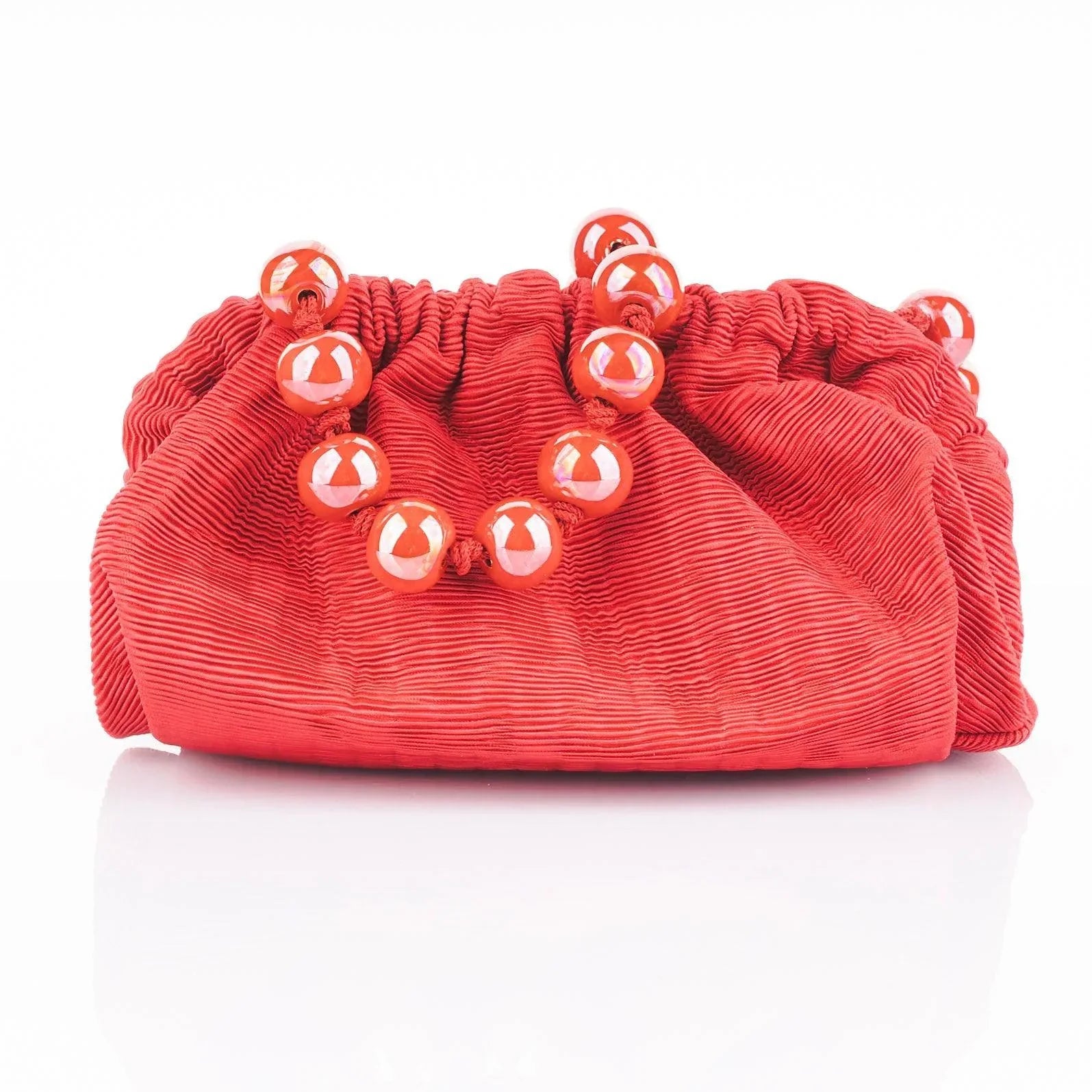 A red pleated mini clutch bag with a ceramic shoulder strap. Ideal for weddings, graduations, and night outs.